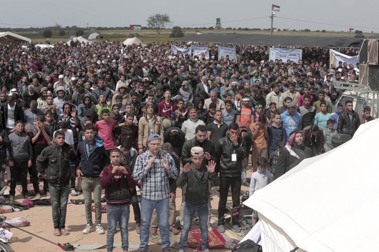 Protesters pray in front of their tents during a demonstration along the Gaza Strip border with Israel, March 30, 2018. AP/Adel Hana