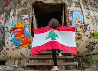 L’État et les Libanais : le divorce Une fille arborant le drapeau libanais à l'entrée de l'Oeuf, structure en béton du Centre ville de Beyrouth. Photographie circulant sur les réseaux sociaux. Crédit Photo: DR (droit réservé)