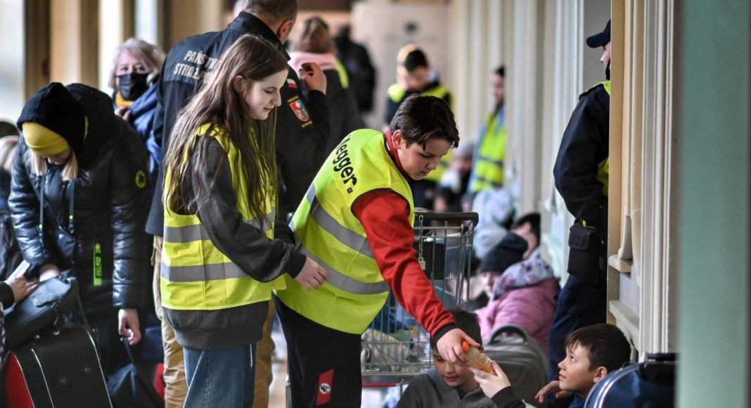 Un volontaire polonais aide un réfugié à la gare de Przemyśl.