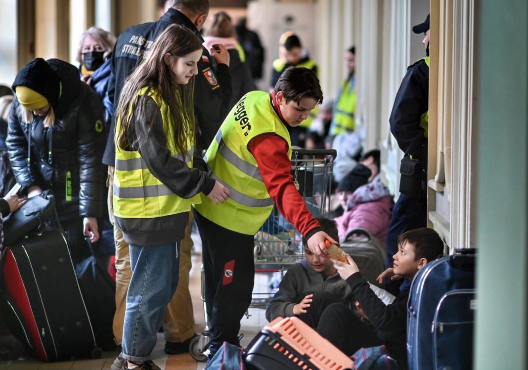 Un volontaire polonais aide un réfugié à la gare de Przemyśl.