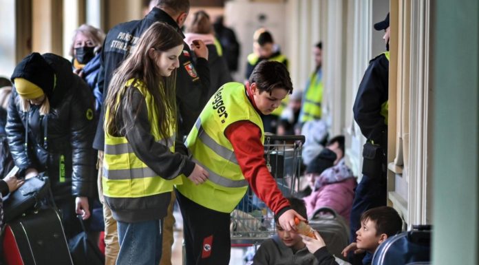 Un volontaire polonais aide un réfugié à la gare de Przemyśl.
