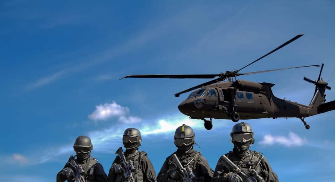 four soldiers carrying rifles near helicopter under blue sky
