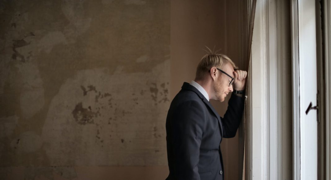 desperate evicted male entrepreneur standing near window