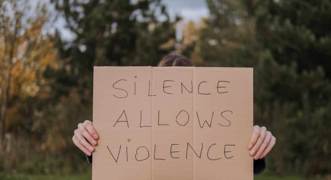 person demonstrating carton with slogan silence allows violence