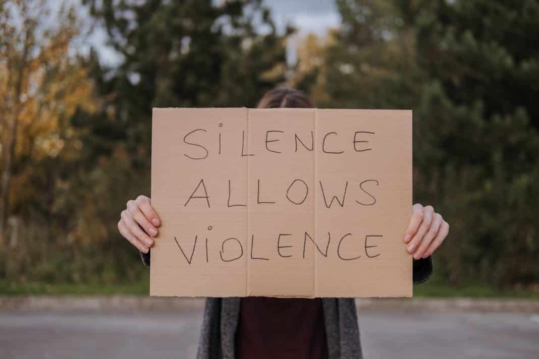 person demonstrating carton with slogan silence allows violence