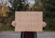 person demonstrating carton with slogan silence allows violence