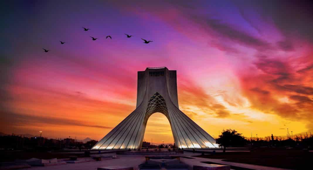birds flying over a building during sunset