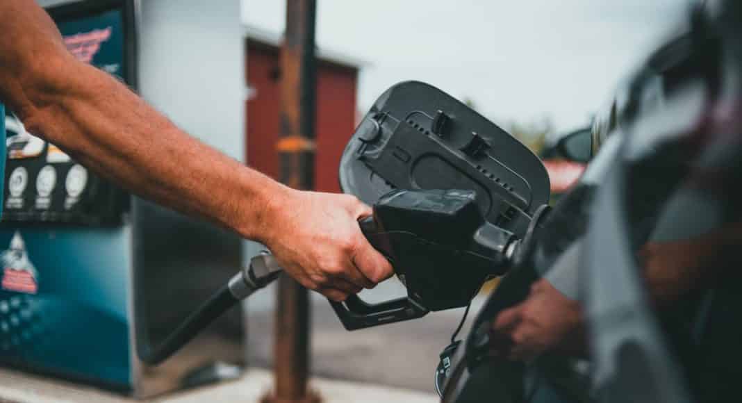 person putting gasoline on a vehicle