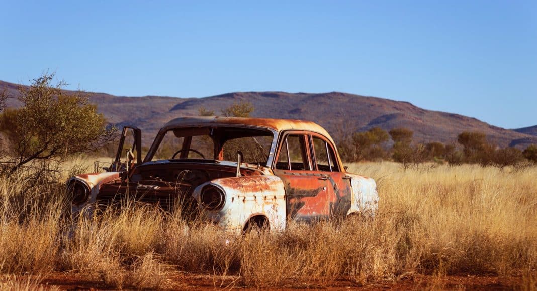 photo of corroded vintage white and red sedan on brown grass