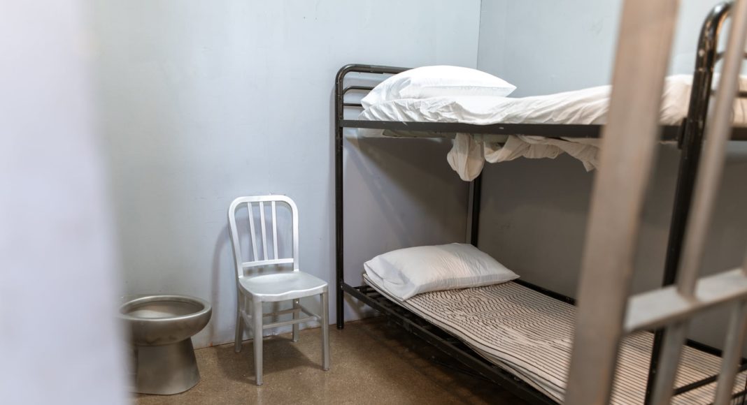 a bunk bed with striped foam mattress in a prison cell