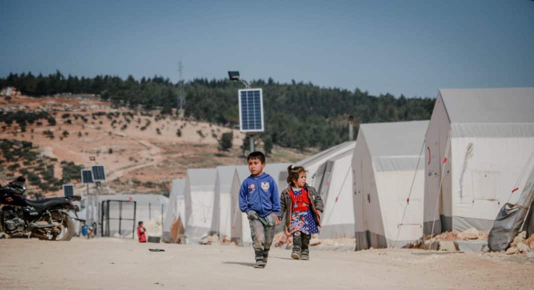 ethnic kids walking on road in refugee camp
