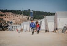 ethnic kids walking on road in refugee camp