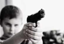 Retrait forcé ou braquage? Le choix des mots est important grayscale photo of a boy aiming toy gun selective focus photography