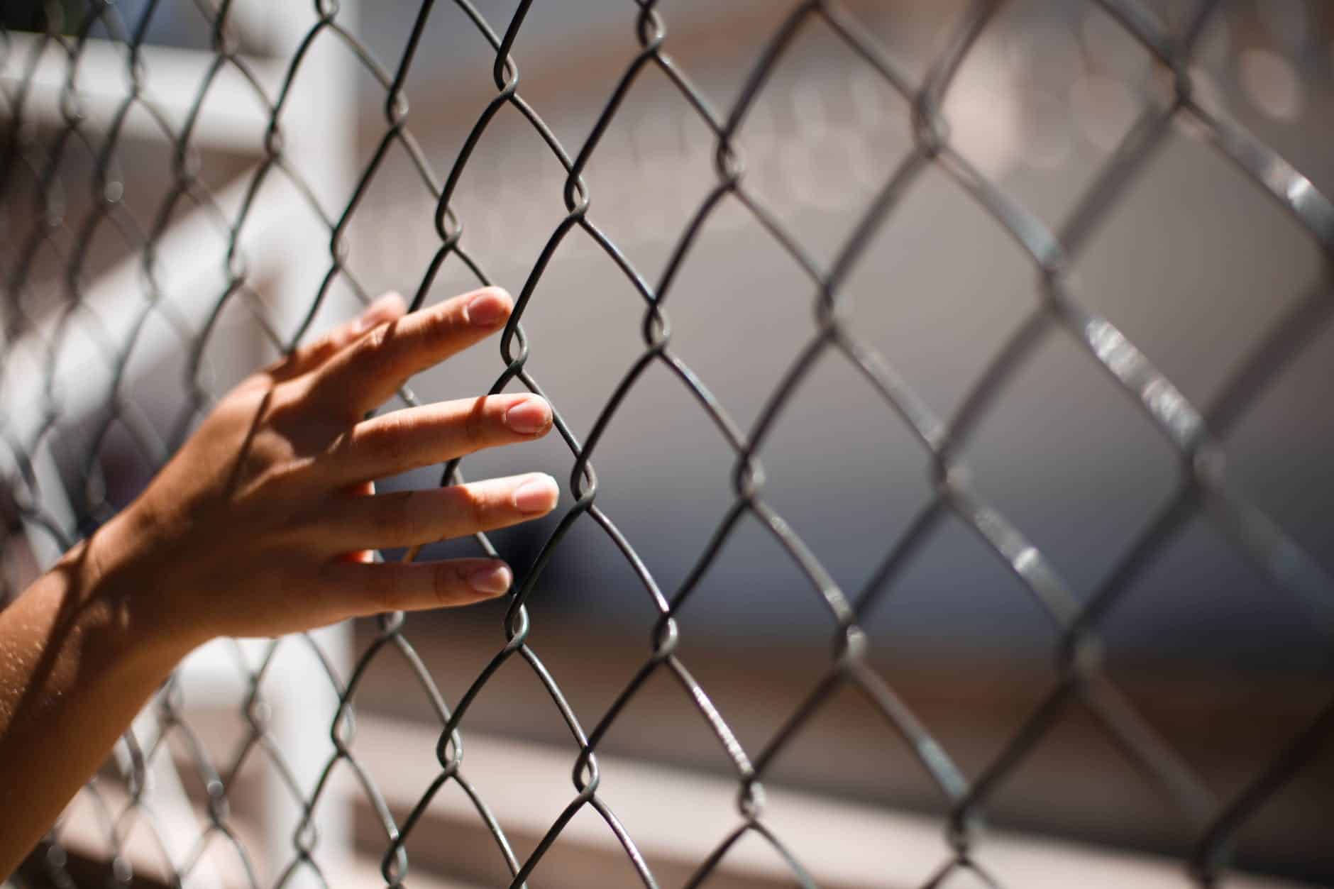 hand of crop person touching grid fence