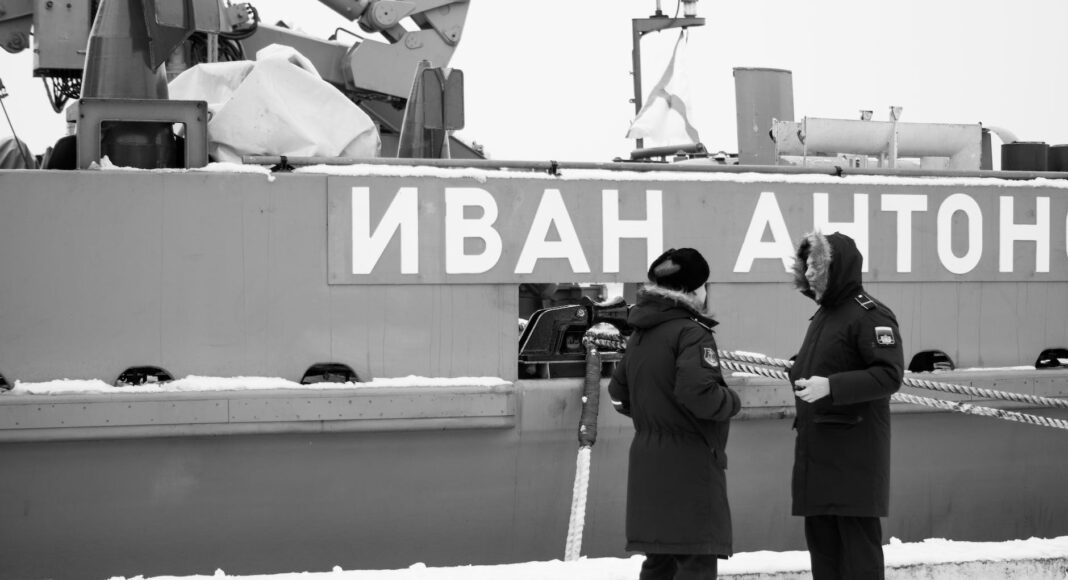 black and white photo of russsoldiers talking in front of warship