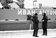 black and white photo of russsoldiers talking in front of warship