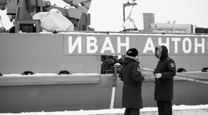 black and white photo of russsoldiers talking in front of warship