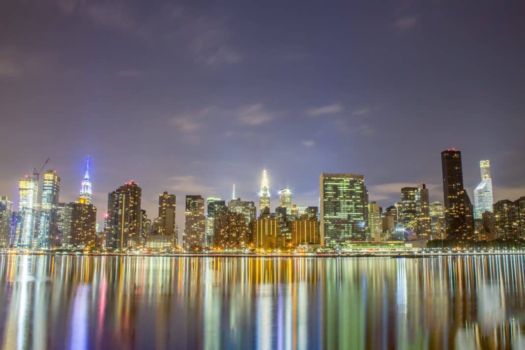 city skyline across body of water during night time