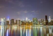 city skyline across body of water during night time