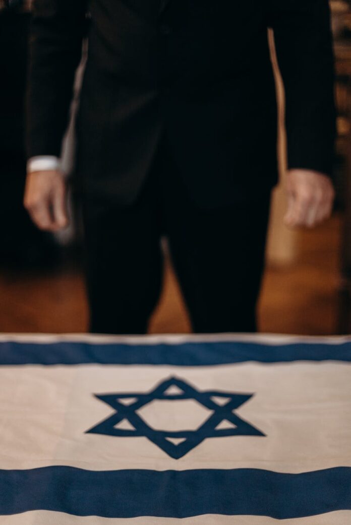 pexels-photo-4033943 man standing next to the flag of israel