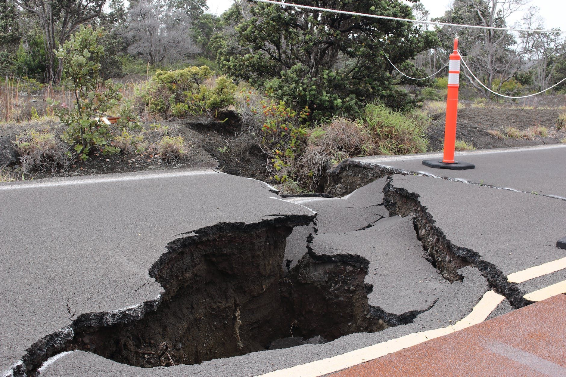 Que faire en cas de tremblement de terre? orange and white traffic pole on cracked gray asphalt road