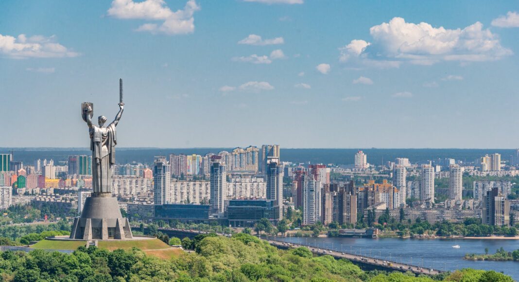 motherland monument among green trees on embankment in kiev