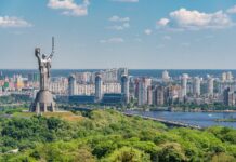 motherland monument among green trees on embankment in kiev