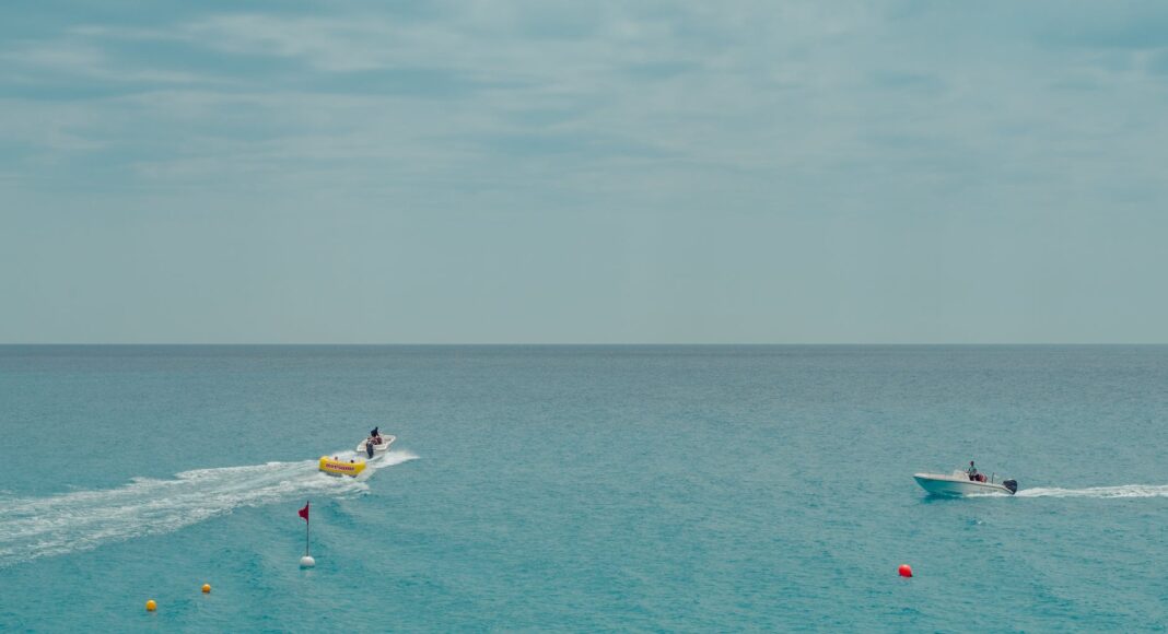 two people rides watercrafts on body of water under clear blue sky