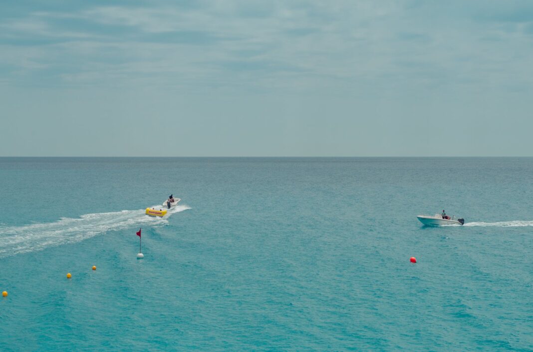 two people rides watercrafts on body of water under clear blue sky