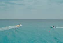 two people rides watercrafts on body of water under clear blue sky