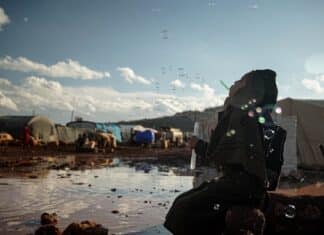 Etats Unis/Syrie/Kurdes 3/4: L’assaut de Daech contre la prison de Gweran (Nord-est de la Syrie) hijabi woman kneeling by puddle in refugee camp blowing bubbles