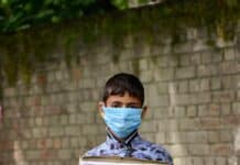 boy in facemask holding placard