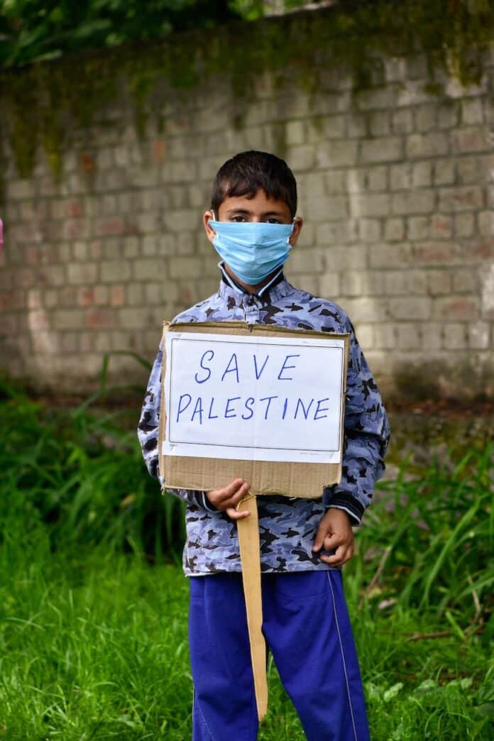 pexels-photo-12018419 boy in facemask holding placard
