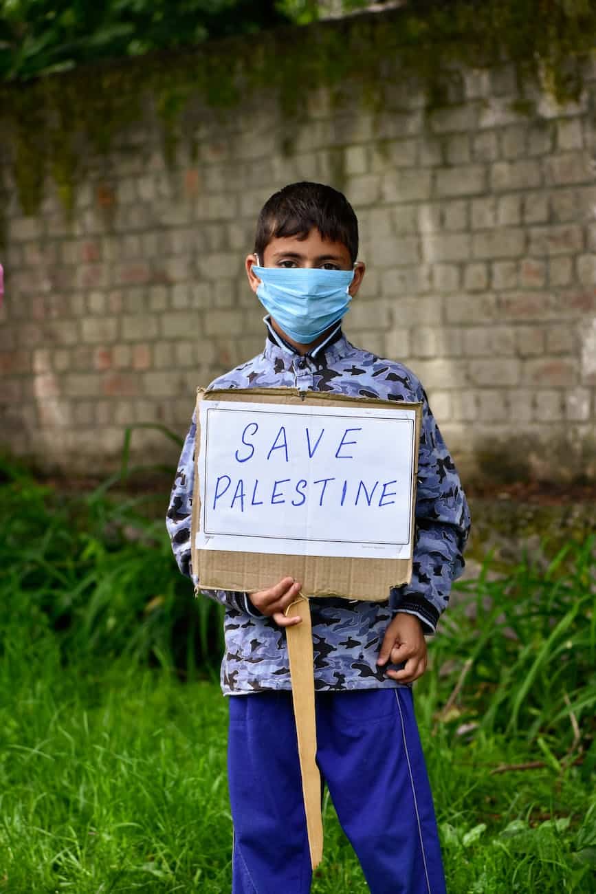 boy in facemask holding placard