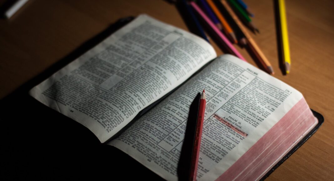 pink pencil on open bible page and pink