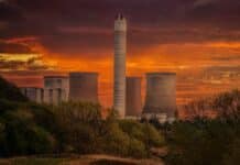 white nuclear plant silo under orange sky at sunset