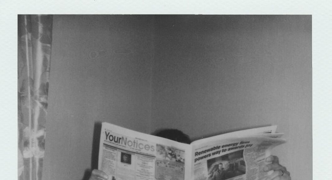 grayscale photography of man reading newspaper