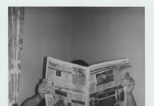 grayscale photography of man reading newspaper