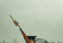 serious soldier with rifle on shoulder marching in park