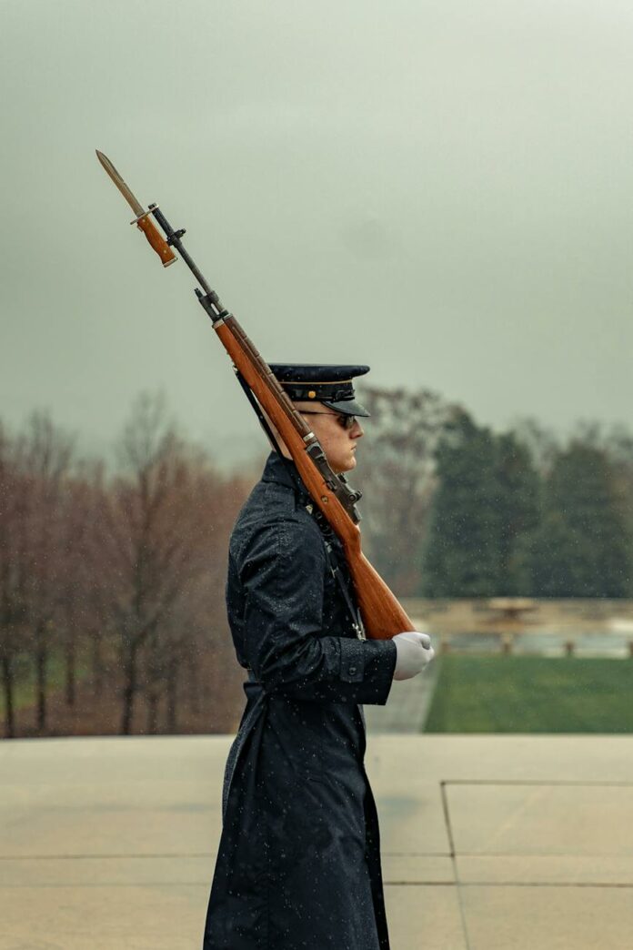 serious soldier with rifle on shoulder marching in park