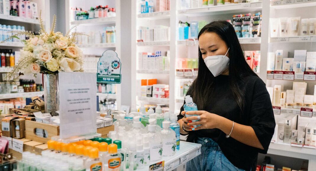 woman with face mask holding an alcohol bottle