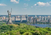 motherland monument among green trees on embankment in kiev