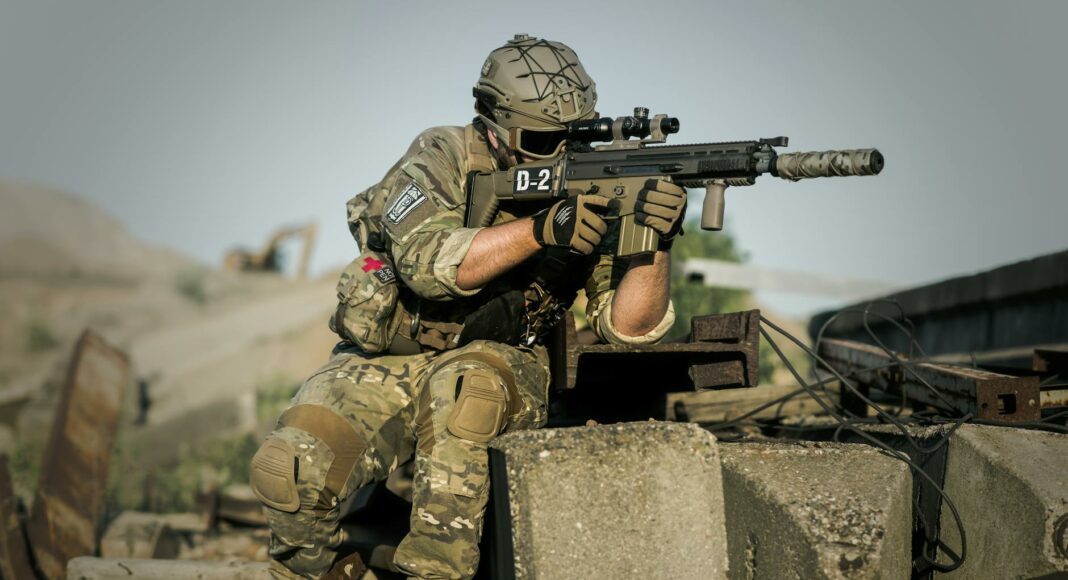 soldier near concrete pillars holding semi automatic gun with scope