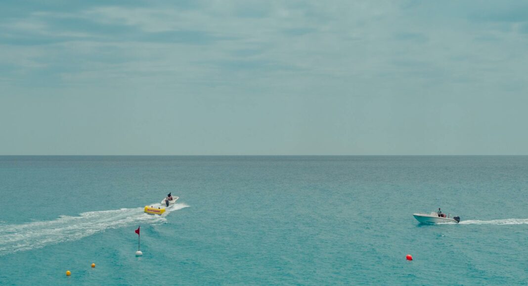 two people rides watercrafts on body of water under clear blue sky