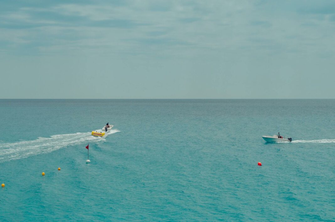 two people rides watercrafts on body of water under clear blue sky