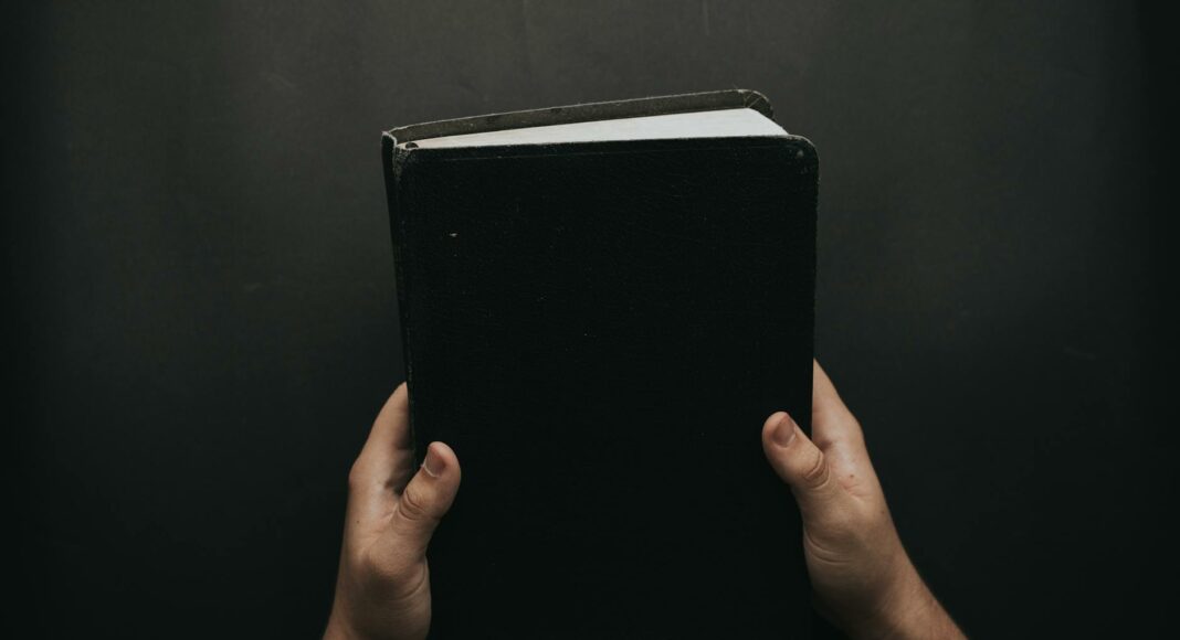 person holding black cover bible