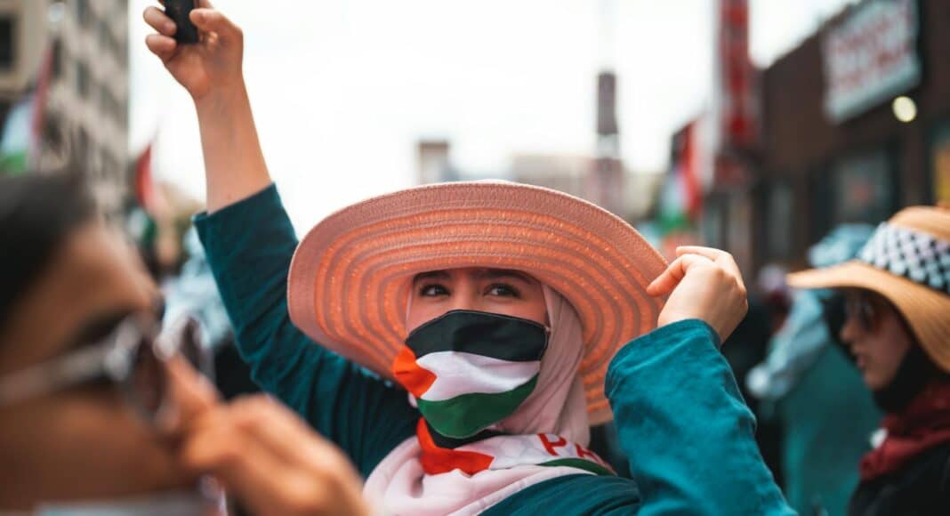 a person with a brown hat wearing palestine flag mask