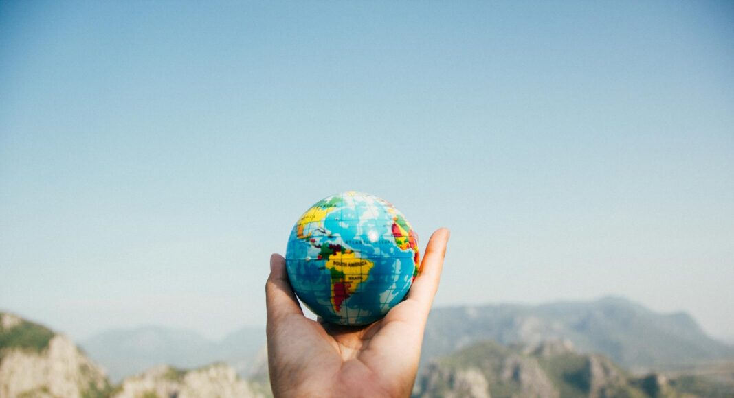 person holding world globe facing mountain