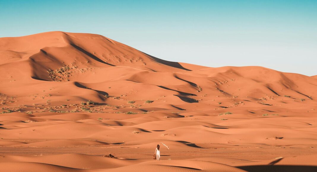 person in white shirt walking on desert