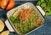a bowl of salad with tomatoes parsley and lemon